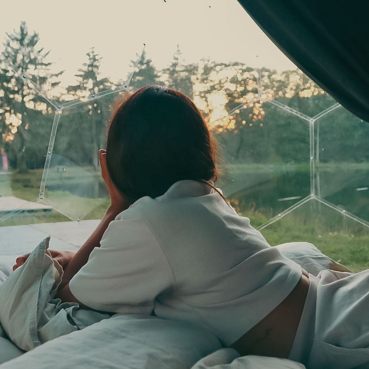 Femme observant la nature depuis le pod de glamping Hypedome