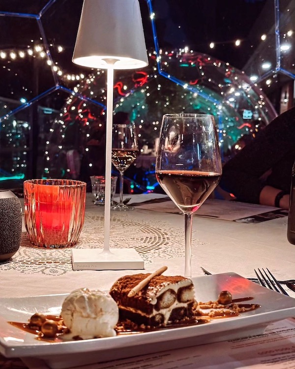 Ein Glas Wein und ein Dessert auf dem Tisch in einer Esskuppel