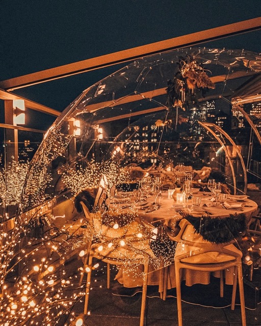 Cena in baccello in un ristorante sul tetto sotto il cielo di mezzanotte, illuminato da luci fiabesche