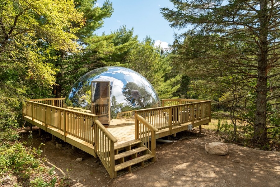 Spiegel-Glamping-Kuppel auf einem Holzdeck