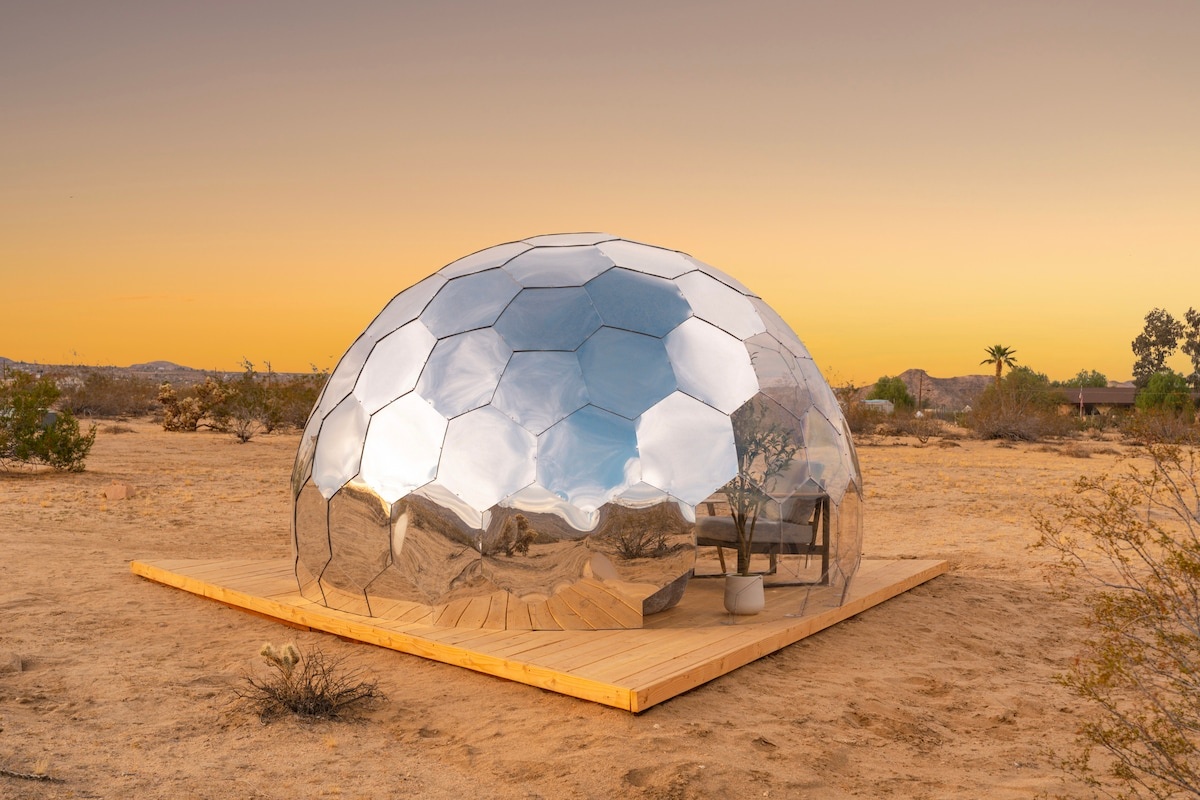 Hypédome en miroir sur une terrasse en bois dans le désert au coucher du soleil