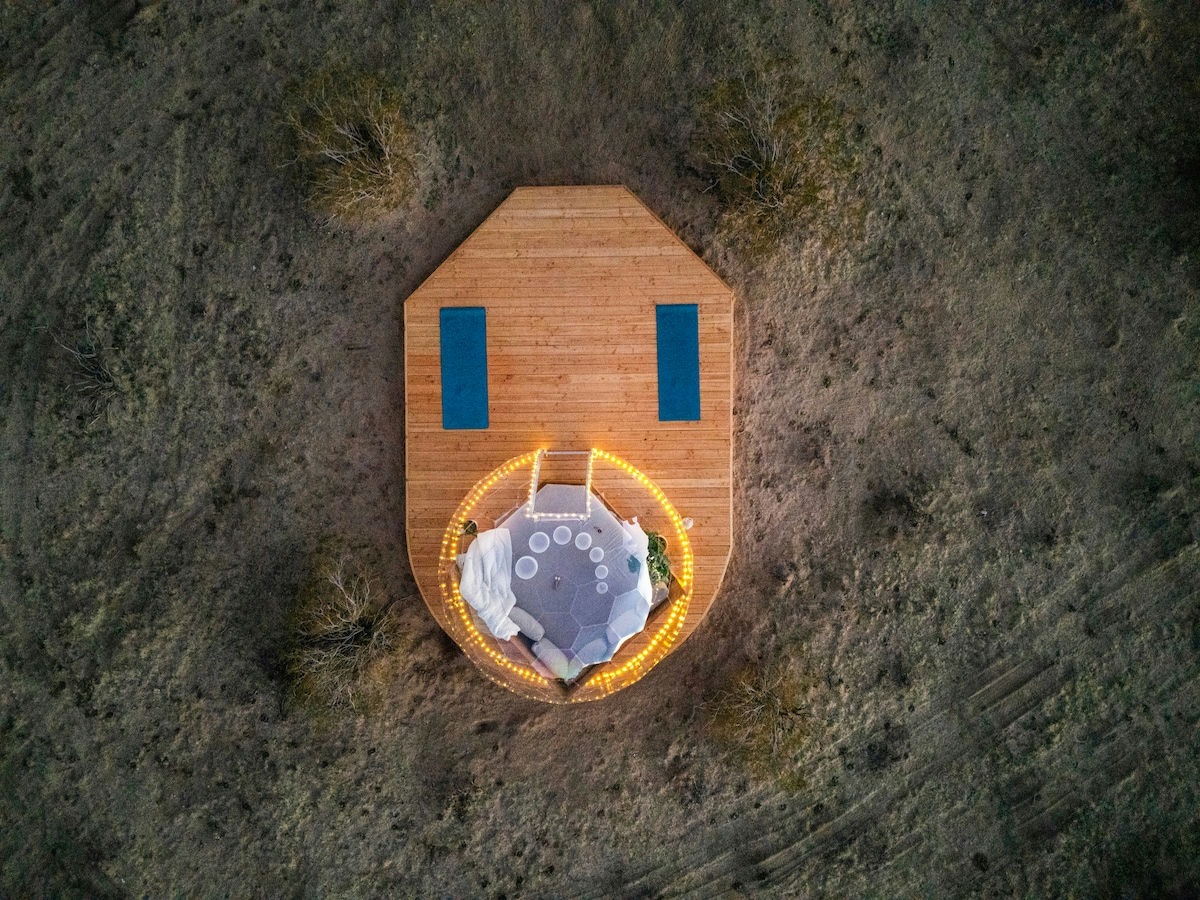 Vista aerea della cupola geodetica Airbnb al crepuscolo con luci fiabesche sul ponte di legno - immagine eroica ad alta conversione