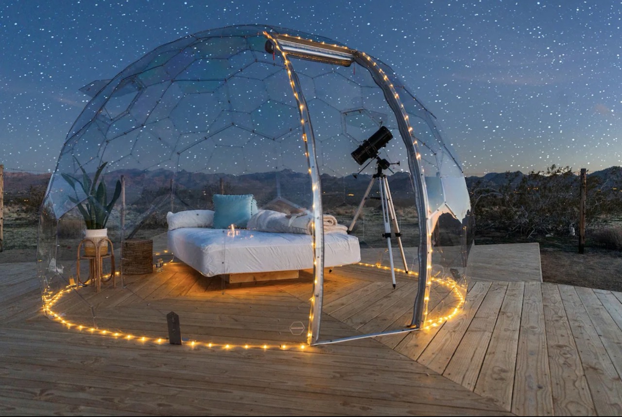 Un Hypedome éclairé d'une lumière tamisée à l'intérieur, le jardin environnant plongé dans l'obscurité pour observer les étoiles