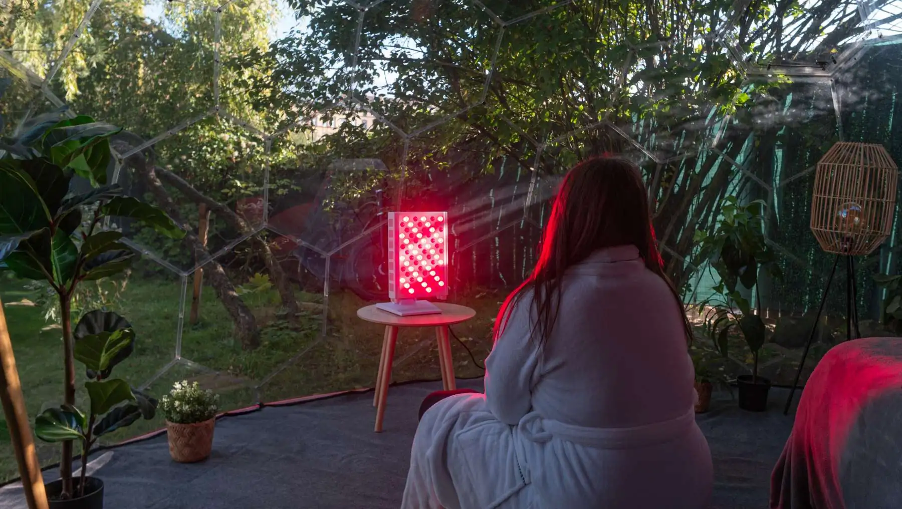 Woman enjoying a red light wellness ritual inside a Hypedome backyard wellness retreat designed for longevity