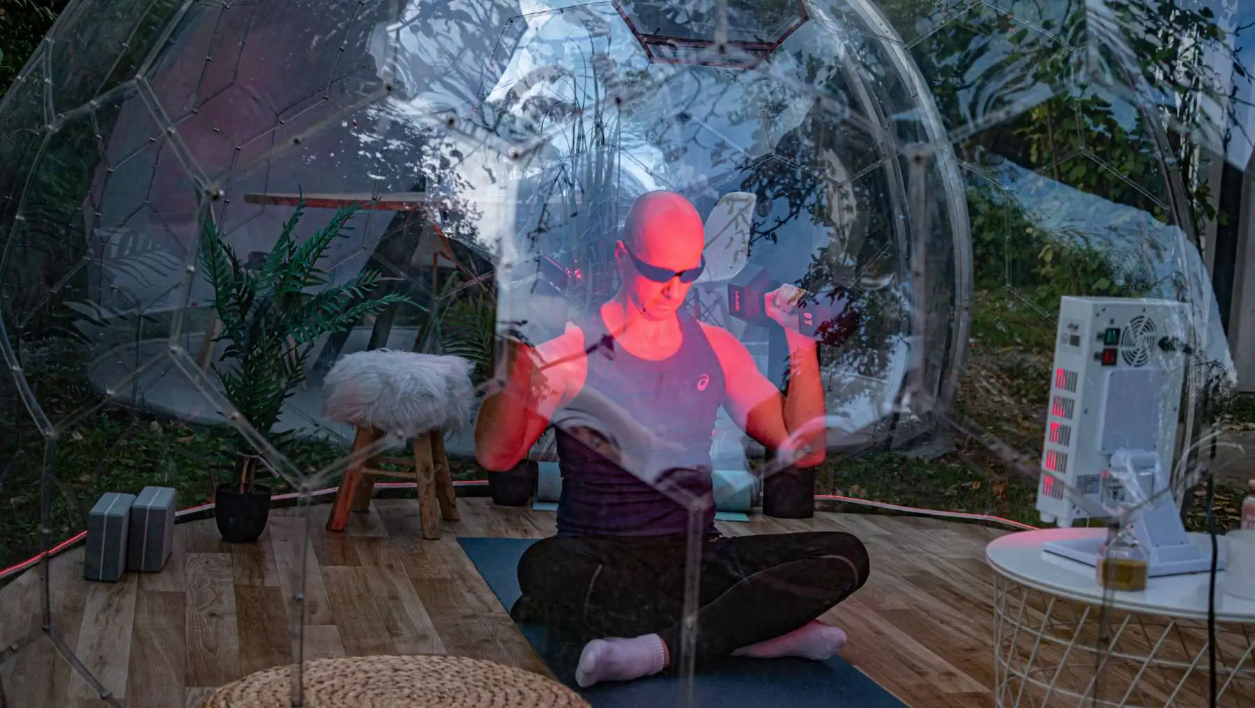 Man working out inside a Hypedome with red light as part of a longevity-focused backyard wellness retreat