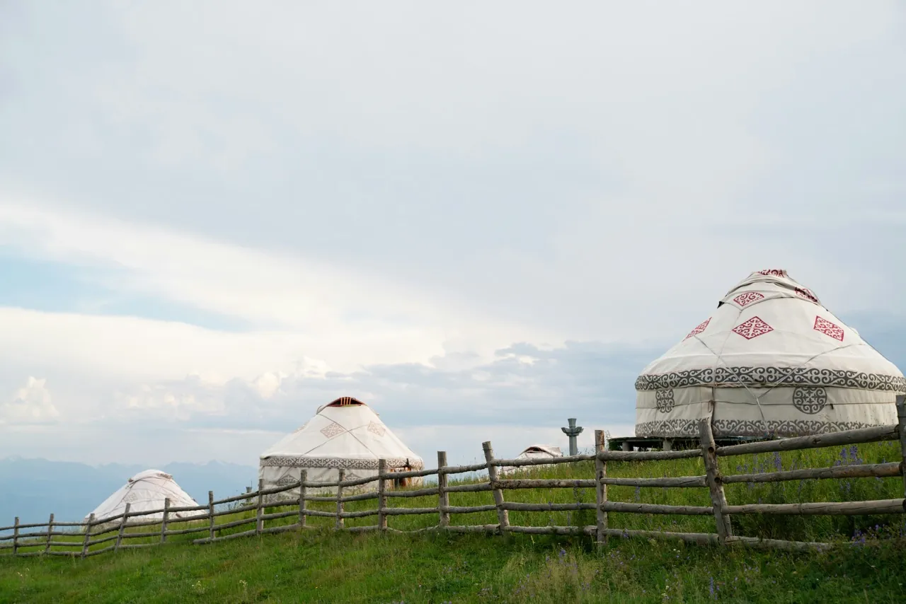 Traditional yurts on a grassy hillside under a summer sky