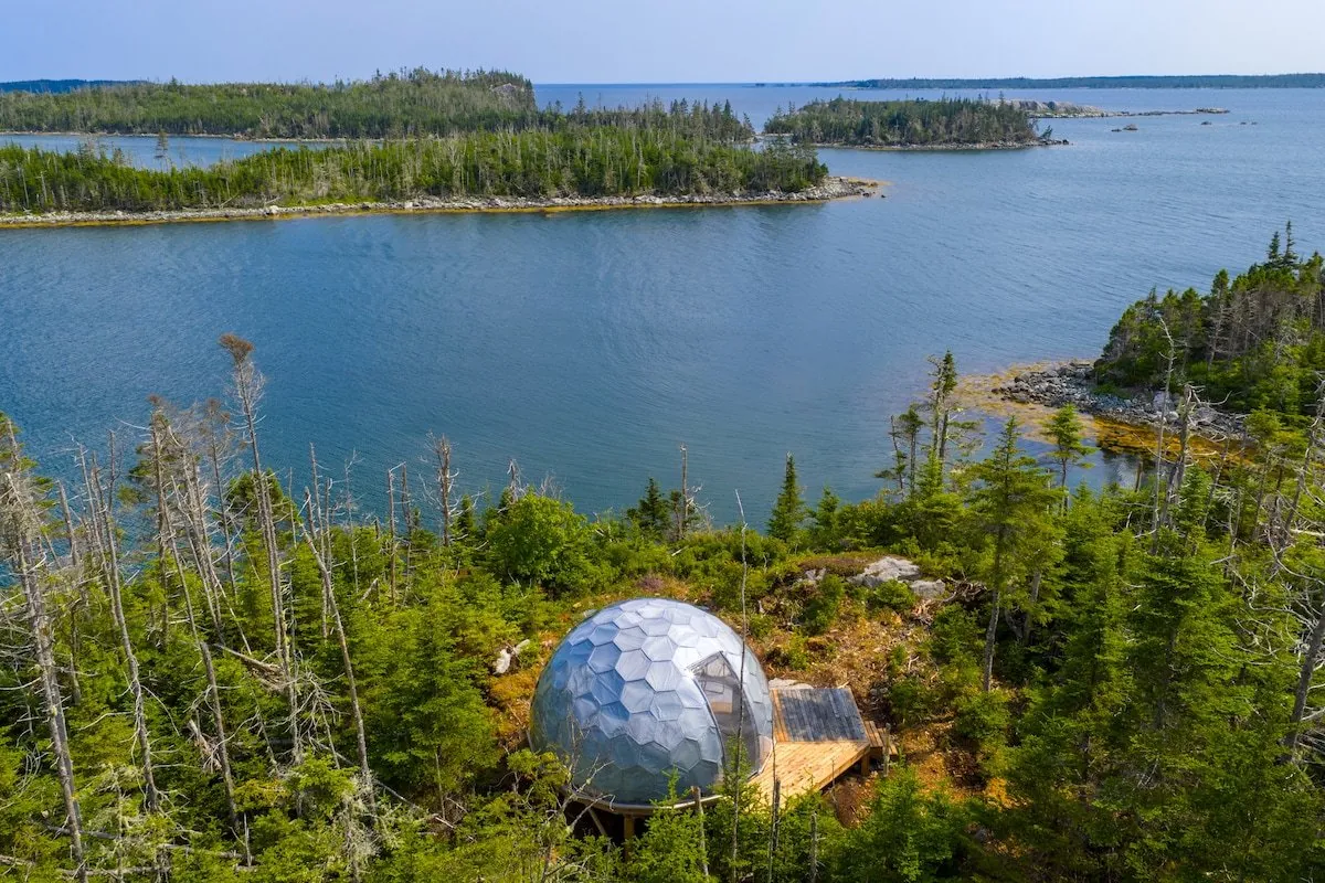 Low drone aerial of dome on forested lake island — the third or fourth hero-gallery shot that consistently performs