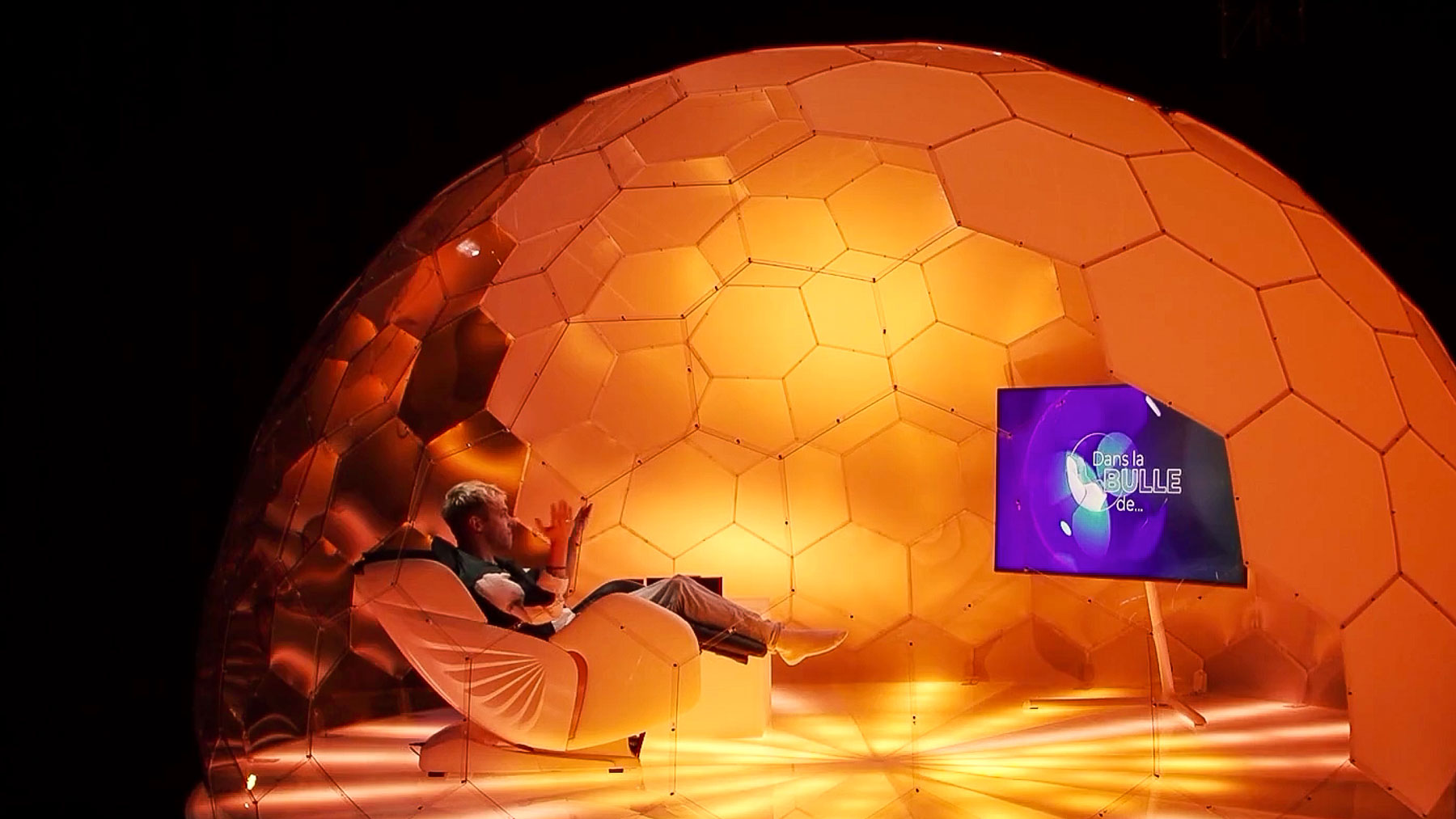 Un homme assis dans le pod d'interview de l'Hypedome dans une émission de télévision