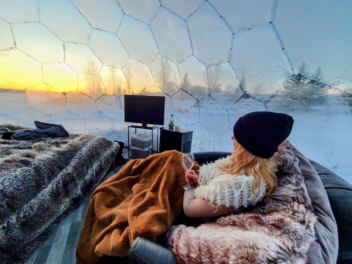 Une femme se reposant dans un lit douillet à l'intérieur d'un glamping.